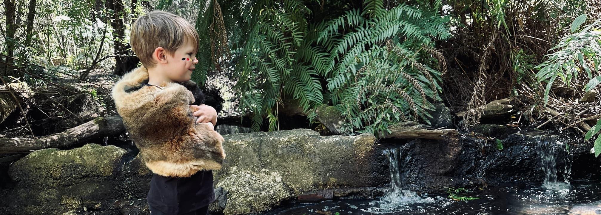 image of child on possum fur laying on a log in nature