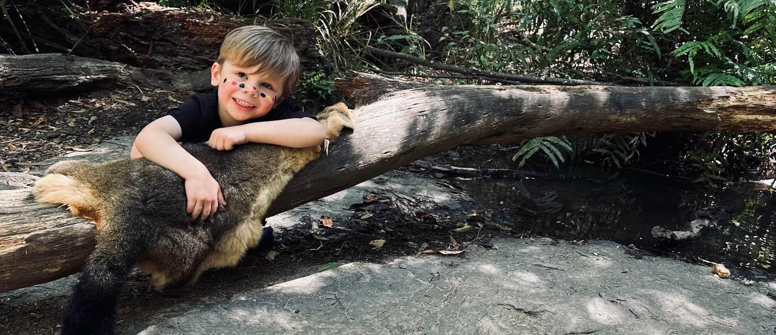 image of child on possum fur laying on a log in nature